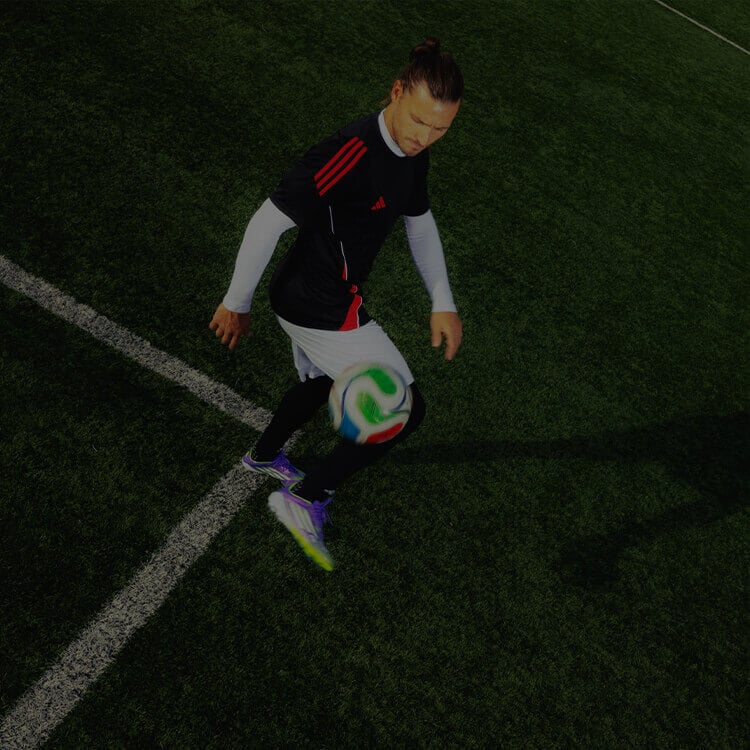 Ragazzo che gioca a calcio vestito con abbigliamento football di adidas